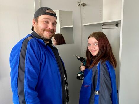 Ein Mann und eine Frau in Arbeitskleidung arbeiten mit einem Akkuschrauber